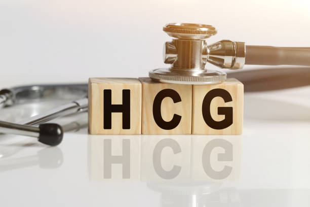 istock HCG the word on wooden cubes, cubes stand on a reflective white surface, on cubes - a stethoscope. 1257698565