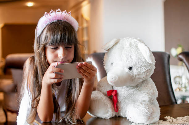 istock Littel girl using mobile phone indoors with her teddy 1257699486