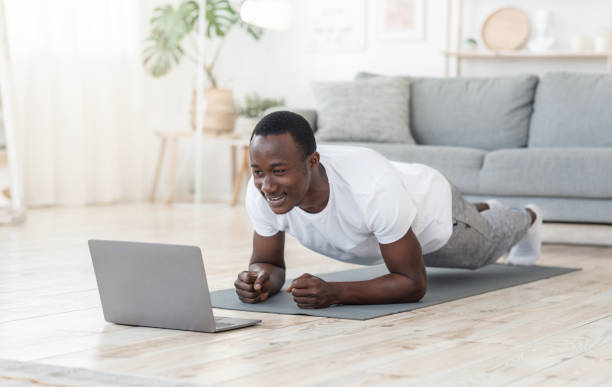 istock Young black man exercising at home, using laptop 1257704229