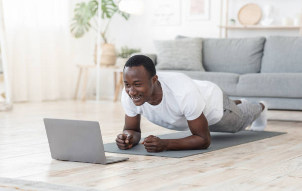 Young black man exercising at home, using laptop Fitness lessons online. Young black man exercising at home, using laptop, copy space bodyweight training photos stock pictures, royalty-free photos & images