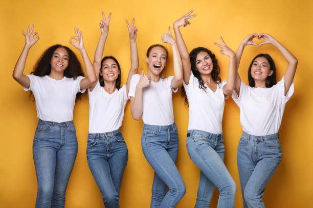 istock Cheerful Diverse Women Gesturing Symbols Smiling Standing On Yellow Background 1257704247