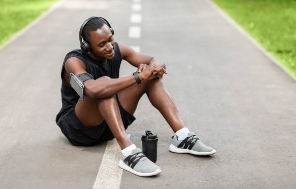 istock Sporty black guy resting and using his smartwatch 1257704313