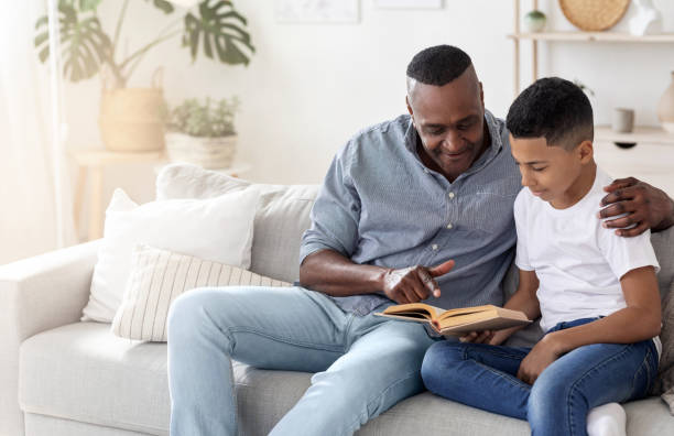 istock Learning Concept. Grandfather explaining text in book to his grandson at home 1257704732