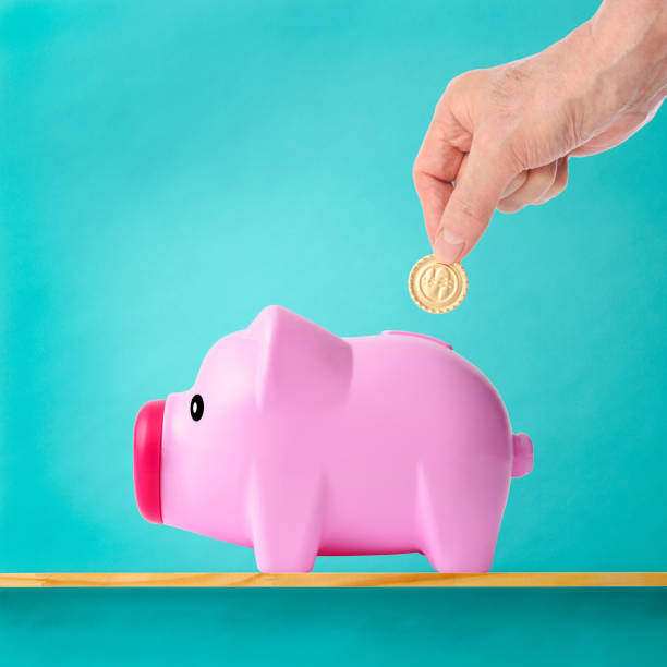 istock Hand inserting gold coins into the piggy bank 1257705375