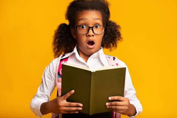 istock Surprised School Girl Holding Book Looking At Camera, Studio Shot 1257707304