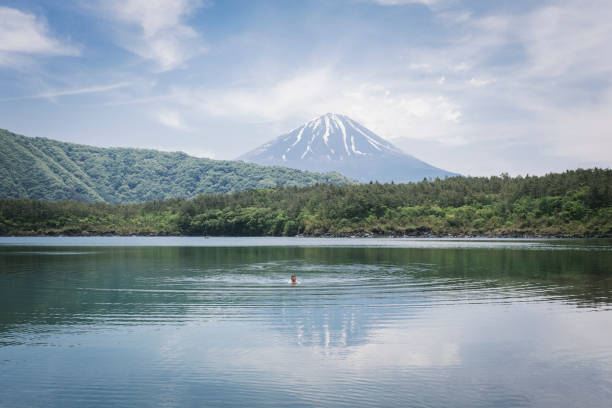 Caucasian man swimming in the lake. Mt Fuji is in the background.