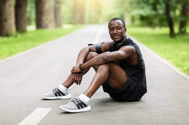 istock Positive black sportsman sitting on path and resting 1257707826