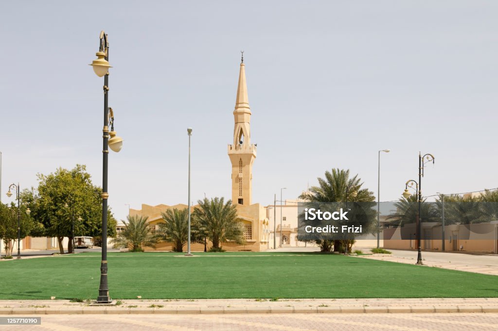 Mosque with minaret in a small place in Saudi Arabia. The lawn in the foreground is artificial turf so that the place looks nicer. Abundance Stock Photo