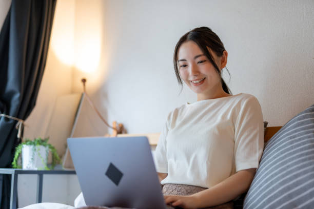 istock Beautiful Asian woman using laptop on bed in quarantine 1257710196