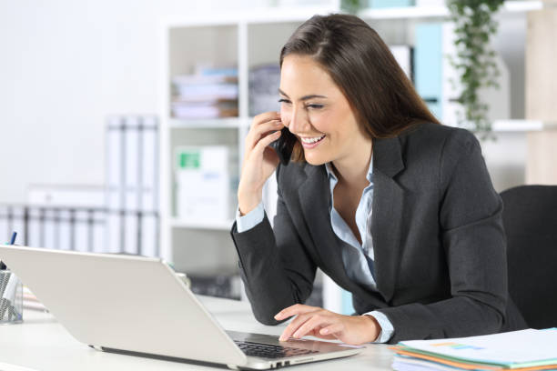 istock Happy executive calls on phone using laptop at office 1257713520
