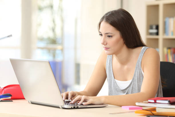 Serious student typing and reading on laptop at home