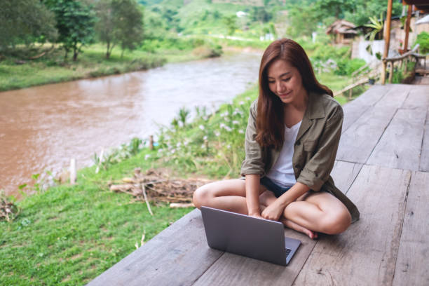 istock a beautiful asian woman working on laptop computer while sitting by the river with mountains and nature background 1257714878