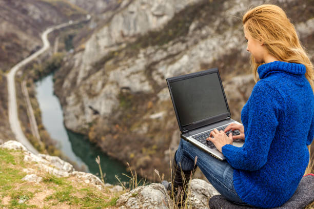 istock Young hiker using her laptop while sitting on top of a mountain 1257717516