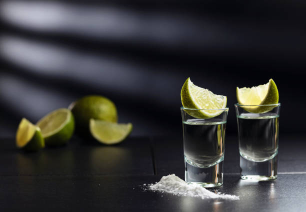 tequila , lime and salt on black table. - tequila shot imagens e fotografias de stock