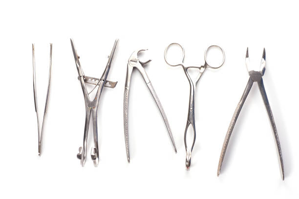 Close-up shot of a doctor holding a tray of medical tools. The tray contains tools such as scissors and tweezers. The doctor is wearing blue rubber gloves whilst holding the tray.