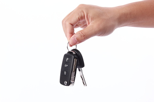 Mano de hombre sosteniendo la llave del coche, aislado sobre fondo blanco photo