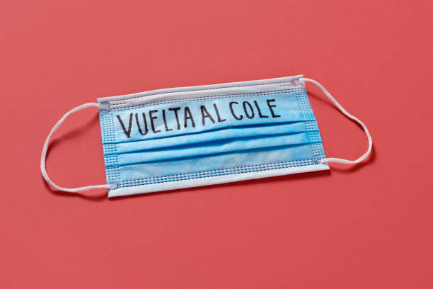istock surgical mask and text back to school in spanish 1257720186