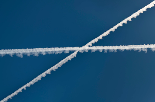 Condensation Trails crossing, Chemtrail against the blue sky. Nikon D850. Converted from RAW.