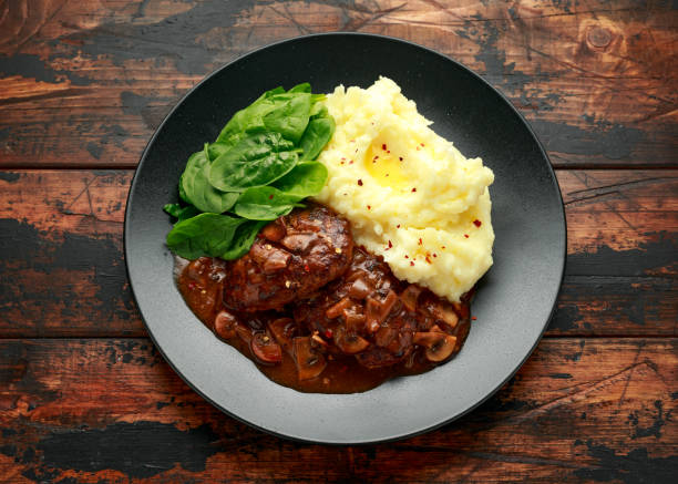 istock Salisbury Steak with mushroom gravy, mashed potatoes and spinach on rustic wooden table 1257722614
