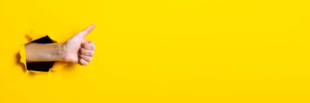 istock Male hand showing thumb up gesture, everything is ok, class on yellow background. Banner. 1257722631
