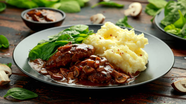 стейк из солсбери с грибным соусом, картофельным пюре и шпинатом - salisbury steak стоковые фото и изображения