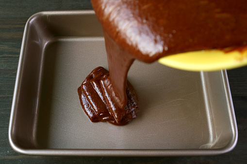 Cake Batter of Flavorful Wholemeal Chocolate Olive Oil Cake Being Poured in Greased Cake Pan photo