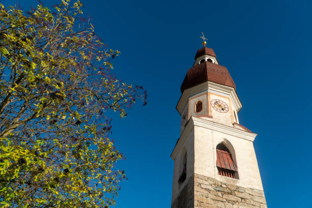 istock High tower with the clock of catholic temple with blue sky background, bottom view 1257725507