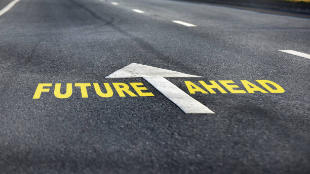 Close ups future ahead word with white arrow and dividing lines on black asphalt road Business challenge concept and effort idea impossible possible stock pictures, royalty-free photos & images