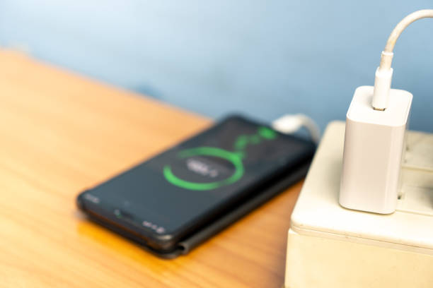 電源アダプタから充電するハイテクモバイルデバイス。 - mobile phone charging power plug adapter ストックフォトと画像