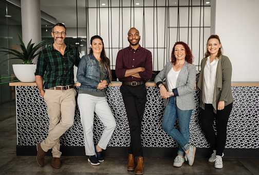 Portrait of a diverse team of smiling businesspeople standing together in the reception area of a modern office