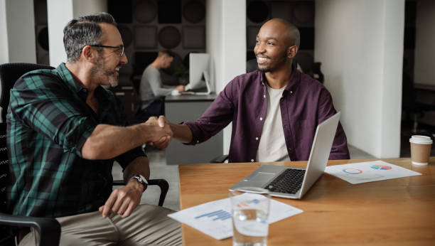 istock Two smiling diverse businessmen shaking hands in an office 1257729341