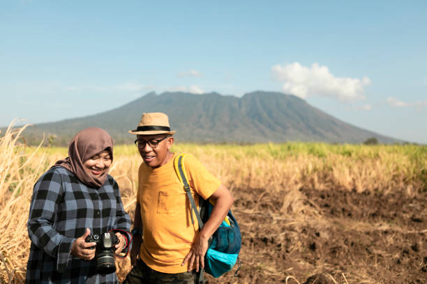 Hiking couple is looking their photography result after long trekking in mountain Hiking couple is resting after long trekking in baluran national park, banyuwangi, East Java, Indonesia muslim photographer stock pictures, royalty-free photos & images