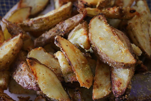 Stock photo showing close-up view of a pile of freshly cooked, homemade, potato wedges in a crispy coating on a plate.