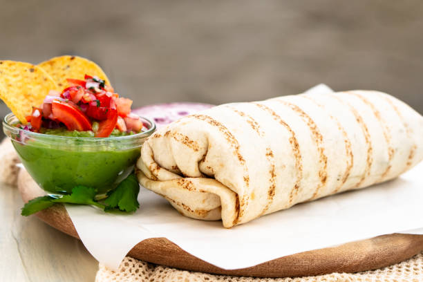 istock Mexican traditional authentic homemade Burrito with pulled pork beef chili con carne served with tomato salad and avocado guacamole and dip sauce 1257733326