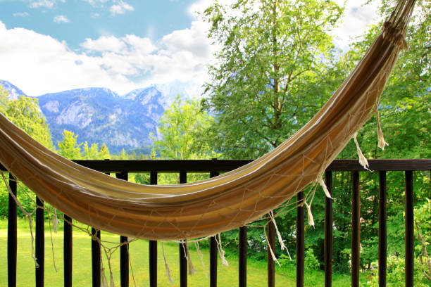 hamaca colgante para relajarse en un balcón de madera y fondo de los alpes. vacaciones idílicas en una hamaca en el balcón con vistas a la cordillera wetterstein montañas. wettersteingebirge - zugspitze mountain - zugspitze mountain mountain germany sky fotografías e imágenes de stock