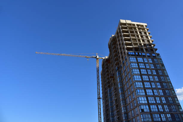 istock Tower crane in action on ble sky background. Multi-storey residential building is being constructed use of crane 1257741568