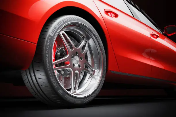 Photo of Wheel of red sports car closeup in studio lighting