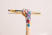 Woman's artist's fist in paints with brushes isolated on a white background. Concept photography for ad or art blog