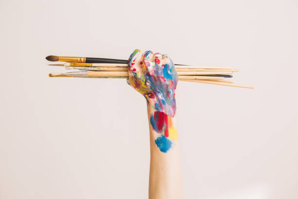 Woman's artist's fist in paints with brushes isolated on a white background. Concept photography for ad or art blog Woman's artist's fist in paints with brushes isolated on a white background. Concept photography for ad or art blog. High quality photo woman painted image stock pictures, royalty-free photos & images