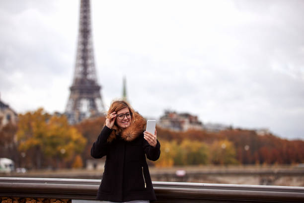 istock Girl using cellphone with Paris city background, Seine river and Eiffel tower. 1257745648