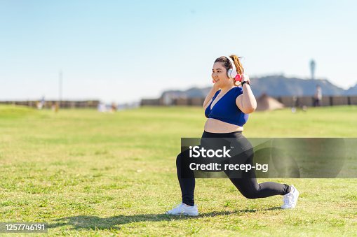 istock Young female athlete doing muscle trainings with dumbbells at public park 1257746191