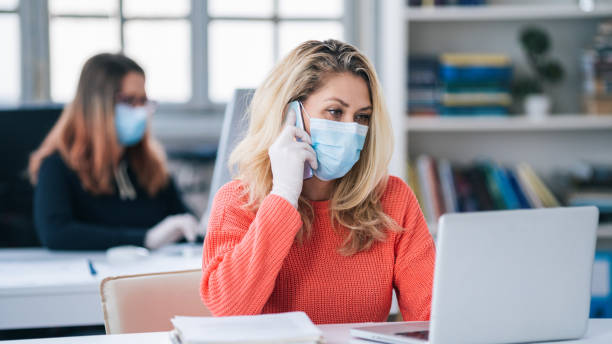 istock Colleagues in the office working while wearing medical face mask during COVID-19 1257746531