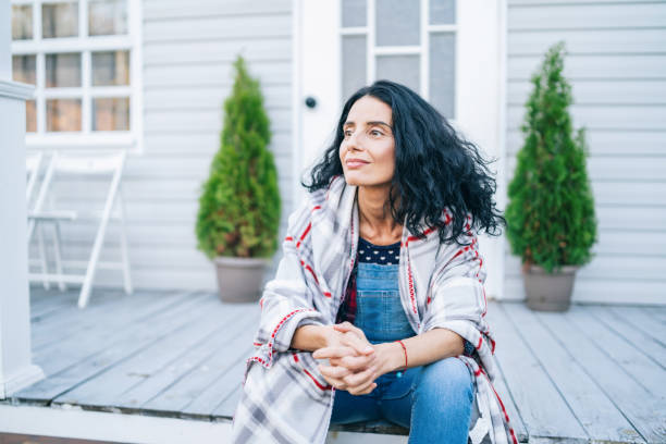 sad mid adult woman sitting on stairs in front of her house - menopause imagens e fotografias de stock