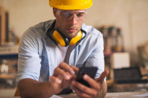 istock Close up of young carpenter using mobile phone 1257747041
