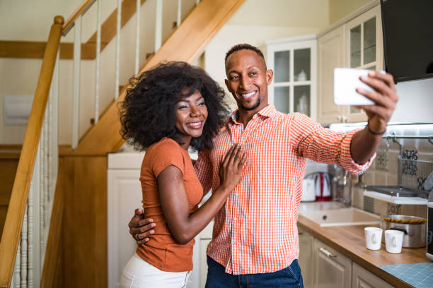 istock Young couple in the kitchen room drinking coffee and taking selfie 1257748409