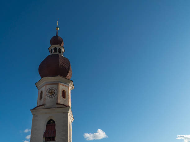 historic church with white and pink facade and red pointed bell tower