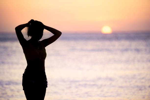 (Selective focus) Stunning view of the silhouette of a girl walking on a beach during a beautiful and romantic sunset. Siargao Island, Philippines. (Selective focus) Stunning view of the silhouette of a girl walking on a beach during a beautiful and romantic sunset. Siargao Island, Philippines. summer fashion philippines palawan stock pictures, royalty-free photos & images