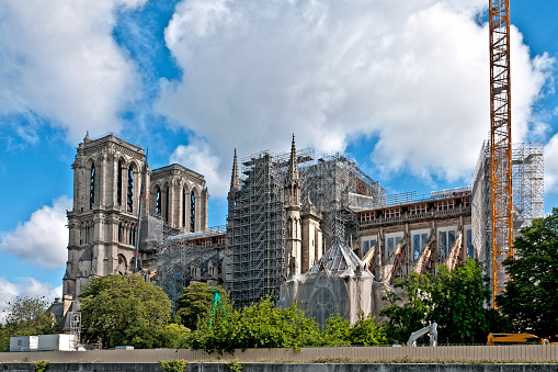 Facade of Notre Dame Cathedral in Paris one year after the fire which destroyed the whole roof in April 15th, 2019. The works have started, with  a scaffolding and reinforcement of buttress and a crane.