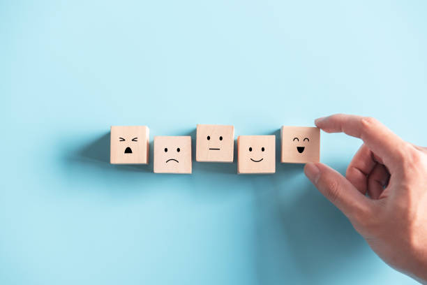 istock Customer service evaluation and satisfaction survey concepts. The client's hand picked the happy face smile face icon symbol on wooden cube. 1257750686