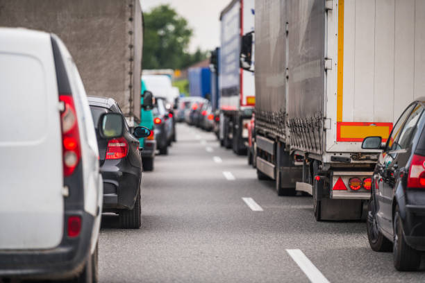 Cars and trucks are stuck in heavy traffic on a multi-lane highway during daytime.